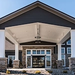 Charter Senior Living of Hopkinsville in Hopkinsville, KY, featuring a beautiful brick exterior, covered drive-through entrance, and grand front doors—offering expert assisted living and memory care services.