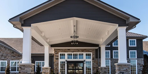 Charter Senior Living of Hopkinsville in Hopkinsville, KY, featuring a beautiful brick exterior, covered drive-through entrance, and grand front doors—offering expert assisted living and memory care services.