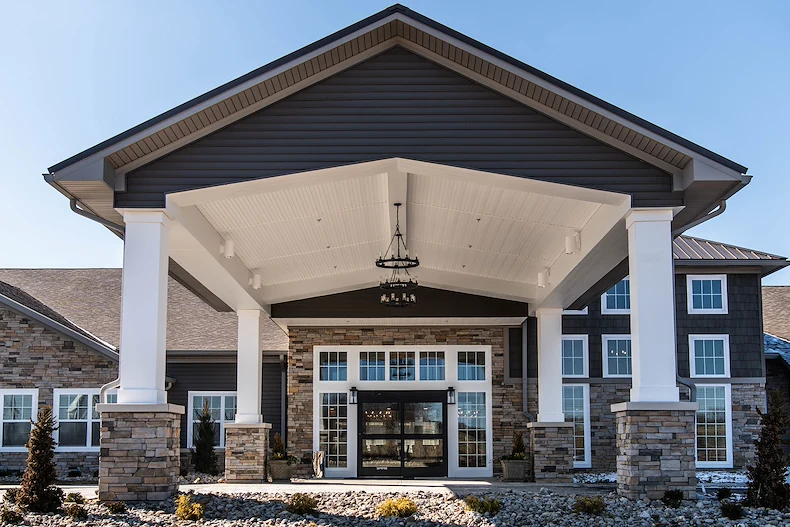 Charter Senior Living of Hopkinsville in Hopkinsville, KY, featuring a beautiful brick exterior, covered drive-through entrance, and grand front doors—offering expert assisted living and memory care services.