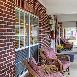 Outdoor furniture set under a covered roof by the brick exterior of Charter Senior Living of Jackson in Jackson, TN, providing a comfortable outdoor gathering space for assisted living and memory care residents.