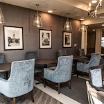 Elegant common area at Charter Senior Living of Hopkinsville in Hopkinsville, KY, featuring velvet chairs, stylish lighting, and spacious tables—designed for comfort in assisted living and memory care.