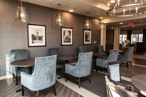Elegant common area at Charter Senior Living of Hopkinsville in Hopkinsville, KY, featuring velvet chairs, stylish lighting, and spacious tables—designed for comfort in assisted living and memory care.
