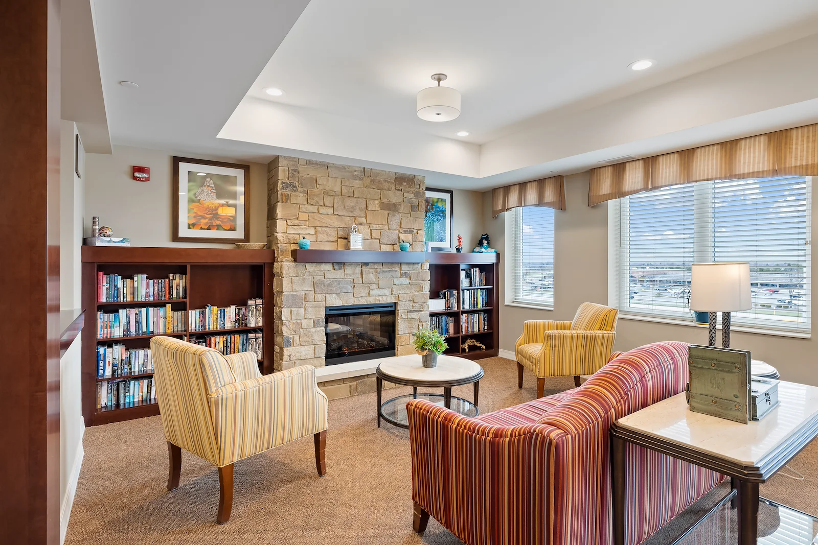 Alto Grayslake, senior living community offering assisted living, memory care, and respite care in Grayslake, IL, library and sitting area by a fireplace