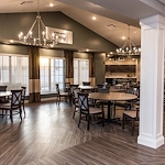 Bright and spacious dining room at Charter Senior Living of Hopkinsville in Hopkinsville, KY, featuring large round tables, elegant lighting, and windows for natural light—designed for comfort in assisted living and memory care.