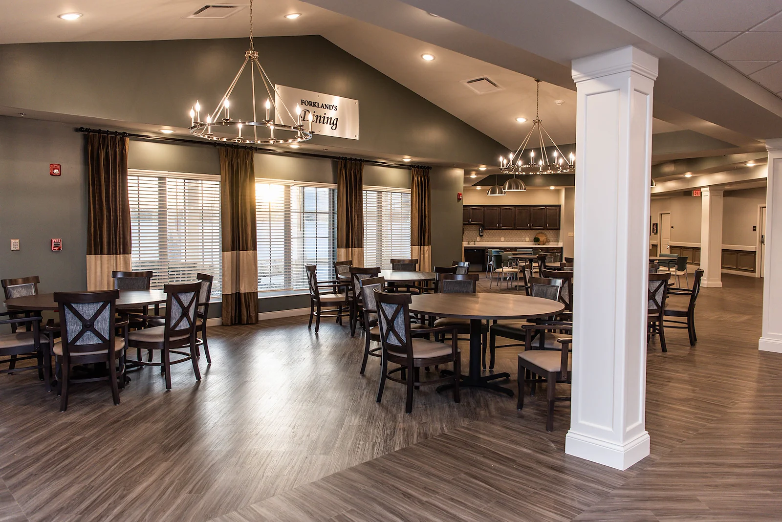 Bright and spacious dining room at Charter Senior Living of Hopkinsville in Hopkinsville, KY, featuring large round tables, elegant lighting, and windows for natural light—designed for comfort in assisted living and memory care.