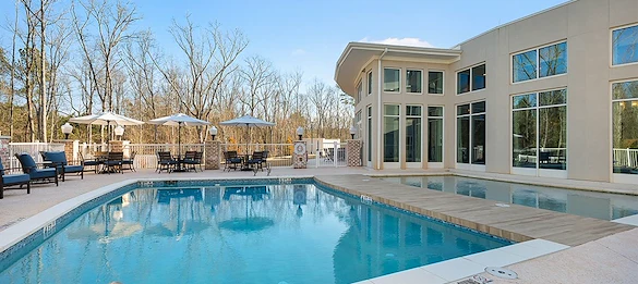Westhill Newnan Crossing senior living community offering assisted living and memory care in Newnan, GA, outdoor pool with tables and chairs nearby for sitting poolside