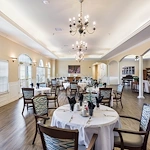 Elegant dining room at Charter Senior Living of Hermitage in Hermitage, TN, with large windows, chandelier lighting, and formal place settings, designed for independent living, assisted living, and memory care residents seeking comfortable senior dining experiences.