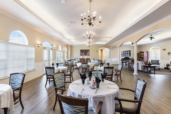 Elegant dining room at Charter Senior Living of Hermitage in Hermitage, TN, with large windows, chandelier lighting, and formal place settings, designed for independent living, assisted living, and memory care residents seeking comfortable senior dining experiences.