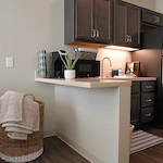 Modern assisted living apartment kitchenette at Charter Senior Living of Hopkinsville in Hopkinsville, KY, featuring a full-size refrigerator and microwave for senior convenience and independence.