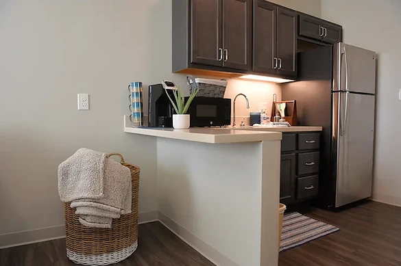 Modern assisted living apartment kitchenette at Charter Senior Living of Hopkinsville in Hopkinsville, KY, featuring a full-size refrigerator and microwave for senior convenience and independence.