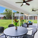 Sunroom with large windows overlooking lush green lawns at Charter Senior Living of Hermitage in Hermitage, TN, featuring comfortable seating and a table, providing a bright, relaxing community space for seniors in independent living, assisted living, and memory care.