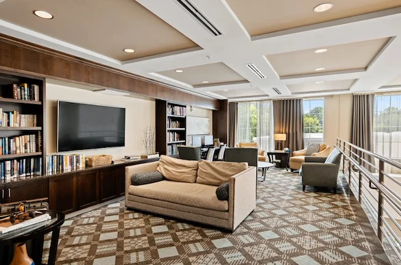 Alto Overland Park, senior living community offering assisted living and memory care in Overland Park, KS, community living room with a variety of seating, a tv, and books