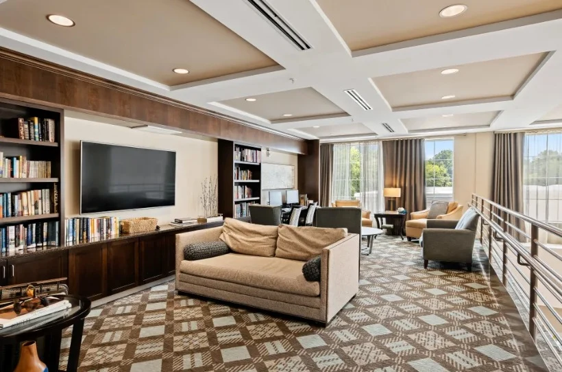 Alto Overland Park, senior living community offering assisted living and memory care in Overland Park, KS, community living room with a variety of seating, a tv, and books