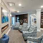Allegro Parkland, senior living community offering independent living, assisted living, memory care, and respite care in Parkland, FL, library and comfortable seating by a fireplace