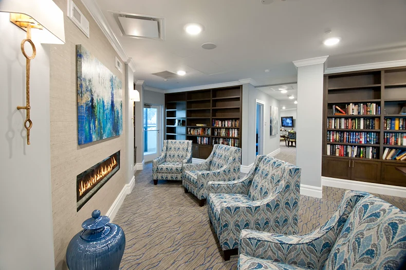 Allegro Parkland, senior living community offering independent living, assisted living, memory care, and respite care in Parkland, FL, library and comfortable seating by a fireplace