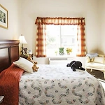 Windsor Heights Senior Living, assisted living and memory care in Beachwood, OH, apartment bedroom with warm natural lighting