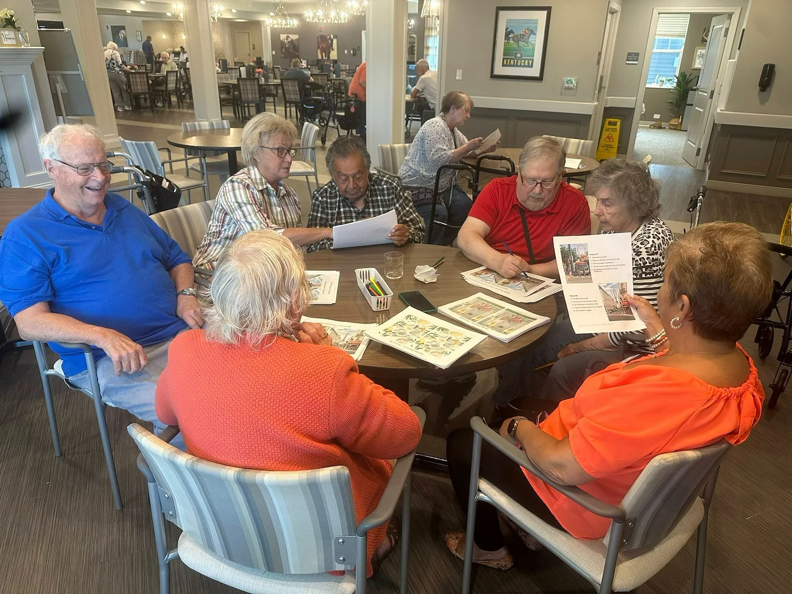 Seniors at Charter Senior Living of Hopkinsville in Hopkinsville, KY, collaborating on a group activity around a wooden table, engaging their minds in assisted living and memory care.