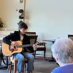 Avamere at Moses Lake senior living community offering independent living, assisted living, and respite care in Moses Lake, WA, residents enjoying a live musical performance with singing and guitar playing