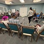 Seniors in assisted living and memory care at Charter Senior Living of Hazel Crest in Hazel Crest, IL, gathered in a common area enjoying a fun indoor bowling activity, as one resident rolls the ball.