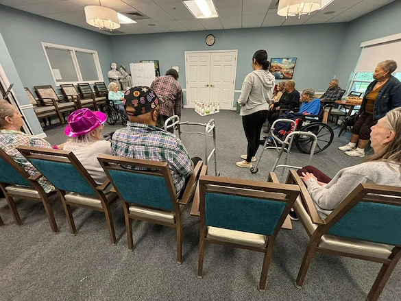 Seniors in assisted living and memory care at Charter Senior Living of Hazel Crest in Hazel Crest, IL, gathered in a common area enjoying a fun indoor bowling activity, as one resident rolls the ball.