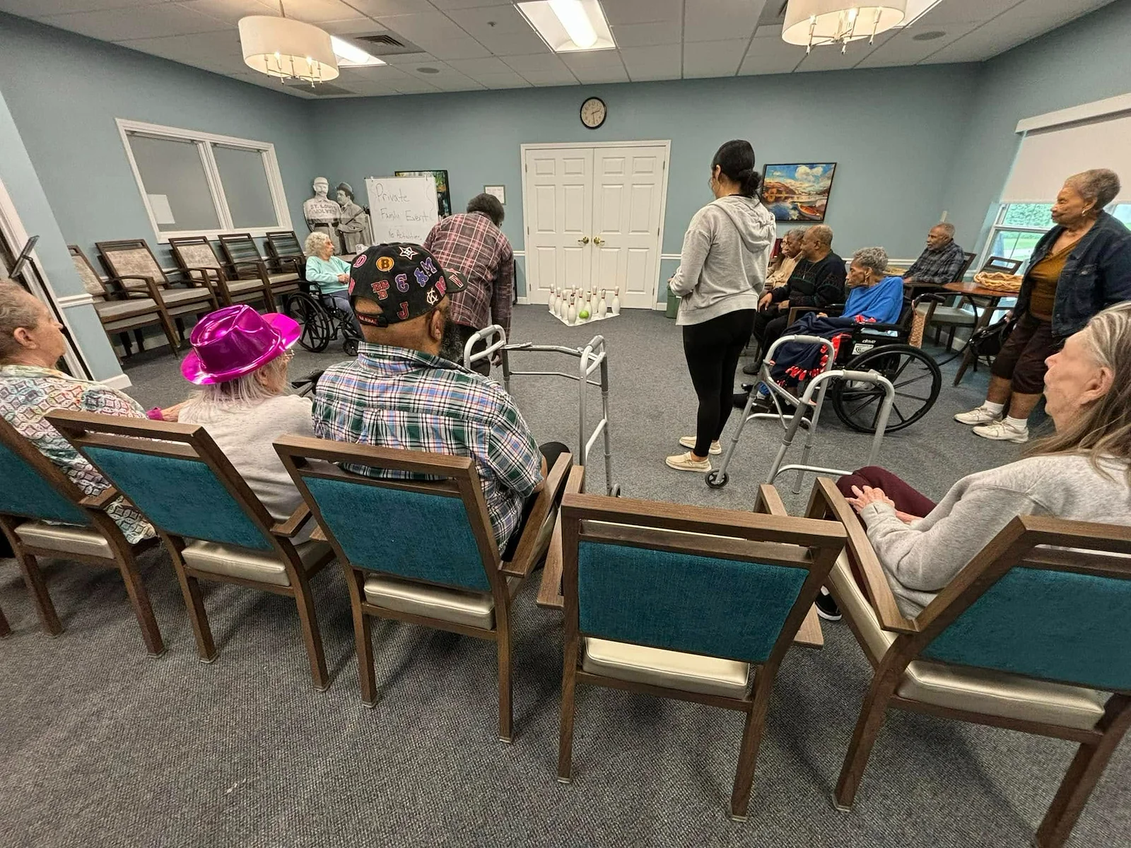 Seniors in assisted living and memory care at Charter Senior Living of Hazel Crest in Hazel Crest, IL, gathered in a common area enjoying a fun indoor bowling activity, as one resident rolls the ball.