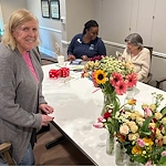 Charter Senior Living of Dedham in Dedham, MA, resident embracing creativity through floral arrangment activitiy