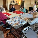 Seniors in assisted living and memory care at Charter Senior Living of Hasmer Lake in Jackson, WI, enjoying a group fabric craft activity that supports creativity, socialization, and cognitive engagement.