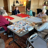 Seniors in assisted living and memory care at Charter Senior Living of Hasmer Lake in Jackson, WI, enjoying a group fabric craft activity that supports creativity, socialization, and cognitive engagement.