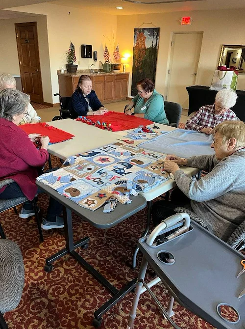 Seniors in assisted living and memory care at Charter Senior Living of Hasmer Lake in Jackson, WI, enjoying a group fabric craft activity that supports creativity, socialization, and cognitive engagement.