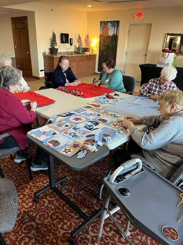 Seniors in assisted living and memory care at Charter Senior Living of Hasmer Lake in Jackson, WI, enjoying a group fabric craft activity that supports creativity, socialization, and cognitive engagement.