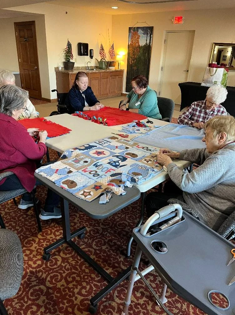 Seniors in assisted living and memory care at Charter Senior Living of Hasmer Lake in Jackson, WI, enjoying a group fabric craft activity that supports creativity, socialization, and cognitive engagement.