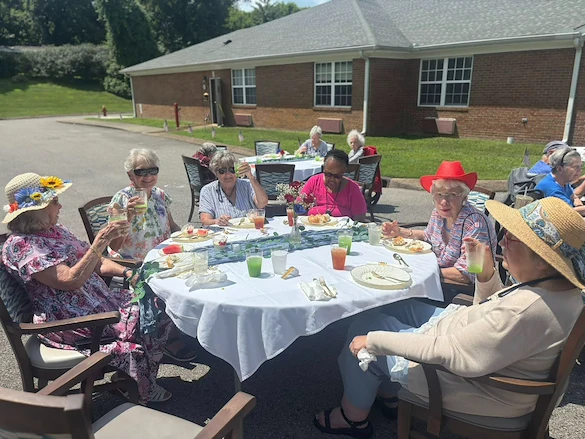 Seniors at Charter Senior Living of Hermitage in Hermitage, TN, dining together outdoors at tables, enjoying pleasant weather and socializing in independent living, assisted living, and memory care.