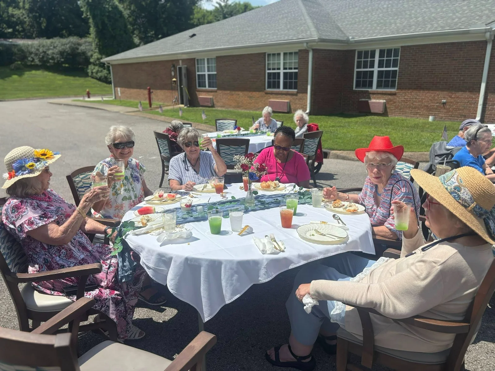 Seniors at Charter Senior Living of Hermitage in Hermitage, TN, dining together outdoors at tables, enjoying pleasant weather and socializing in independent living, assisted living, and memory care.