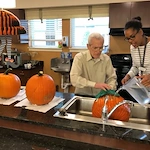 Harvester Place Senior Assisted Living Memory Care in Burr Ridge, IL resident washing a pumpkin