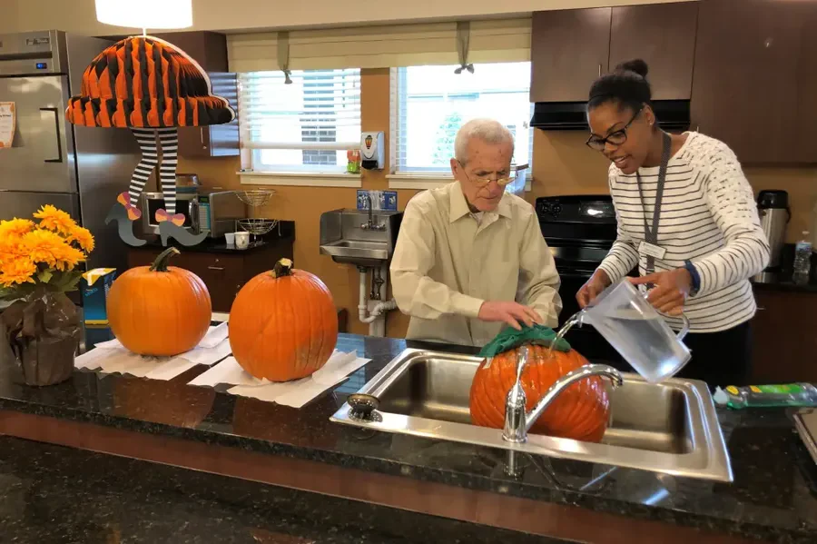 Harvester Place Senior Assisted Living Memory Care in Burr Ridge, IL resident washing a pumpkin