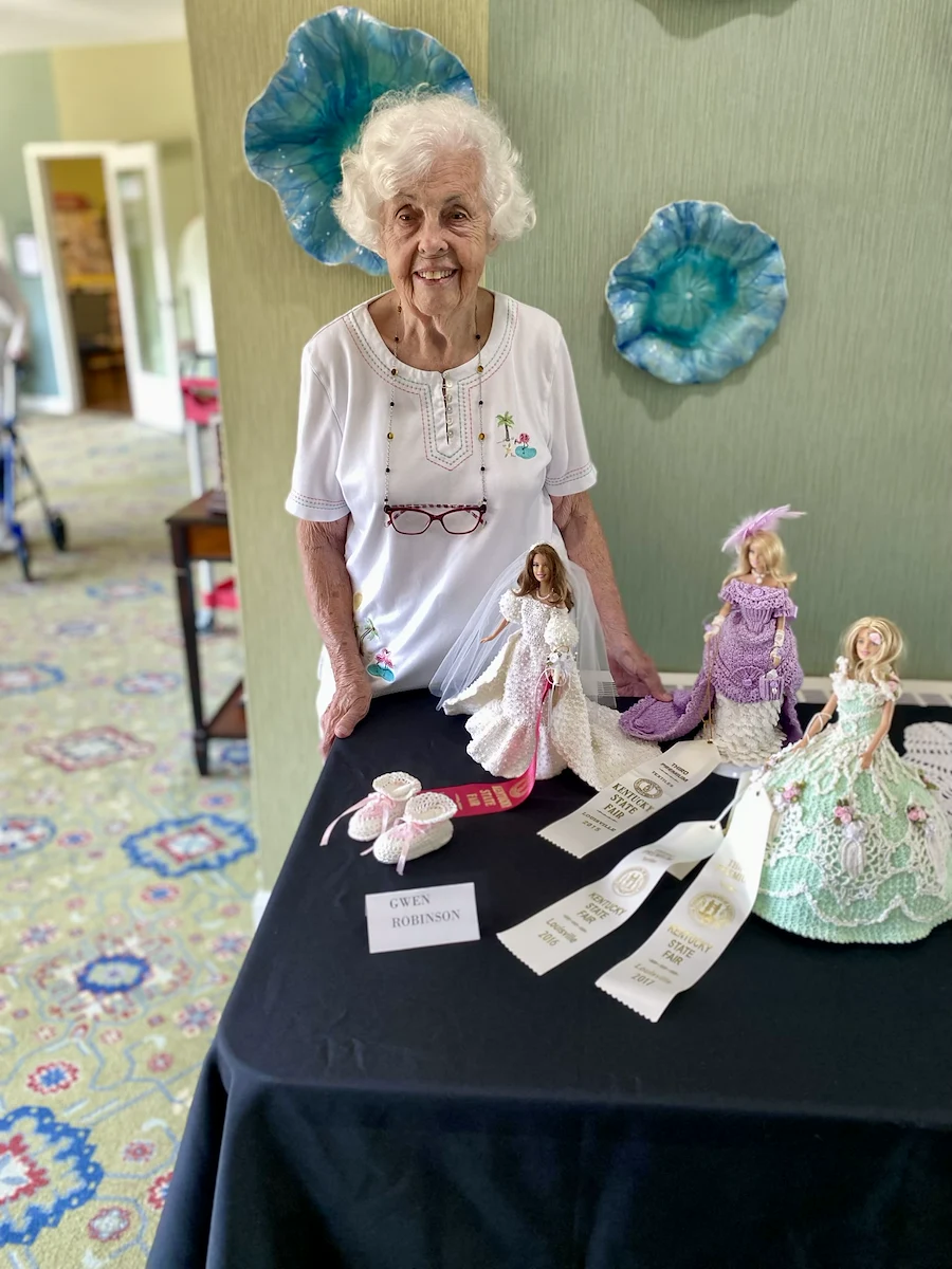 Wesley Manor Assisted Living Community offering assisted living and continuing care retirement community (CCRC) services in Louisville, KY, senior woman standing by State Fair Barbie outfits project