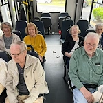 Seniors smiling inside a community van from Charter Senior Living of Jackson in Jackson, TN, heading out on a group outing, showcasing social connection and active living in assisted living and memory care.