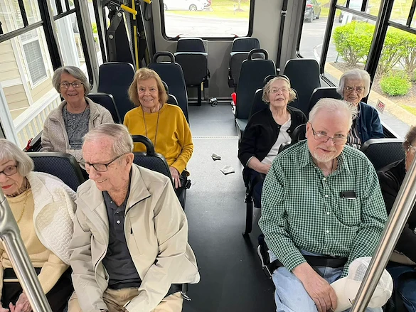 Seniors smiling inside a community van from Charter Senior Living of Jackson in Jackson, TN, heading out on a group outing, showcasing social connection and active living in assisted living and memory care.