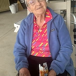 Smiling resident at Charter Senior Living of Hopkinsville in Hopkinsville, KY, enjoying Goldfish crackers outside, promoting happiness and wellness in assisted living and memory care.