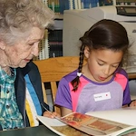 Willowbrook Place Senior Assisted Living Memory Care in Littleton, CO resident reading a book with a child