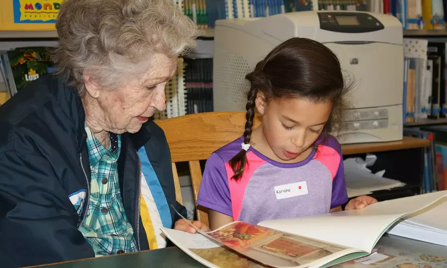 Willowbrook Place Senior Assisted Living Memory Care in Littleton, CO resident reading a book with a child