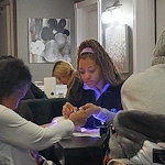 American House Westland Venoy senior living community offering independent living, assisted living, and respite care in Westland, MI, resident getting her nails done by a staff member