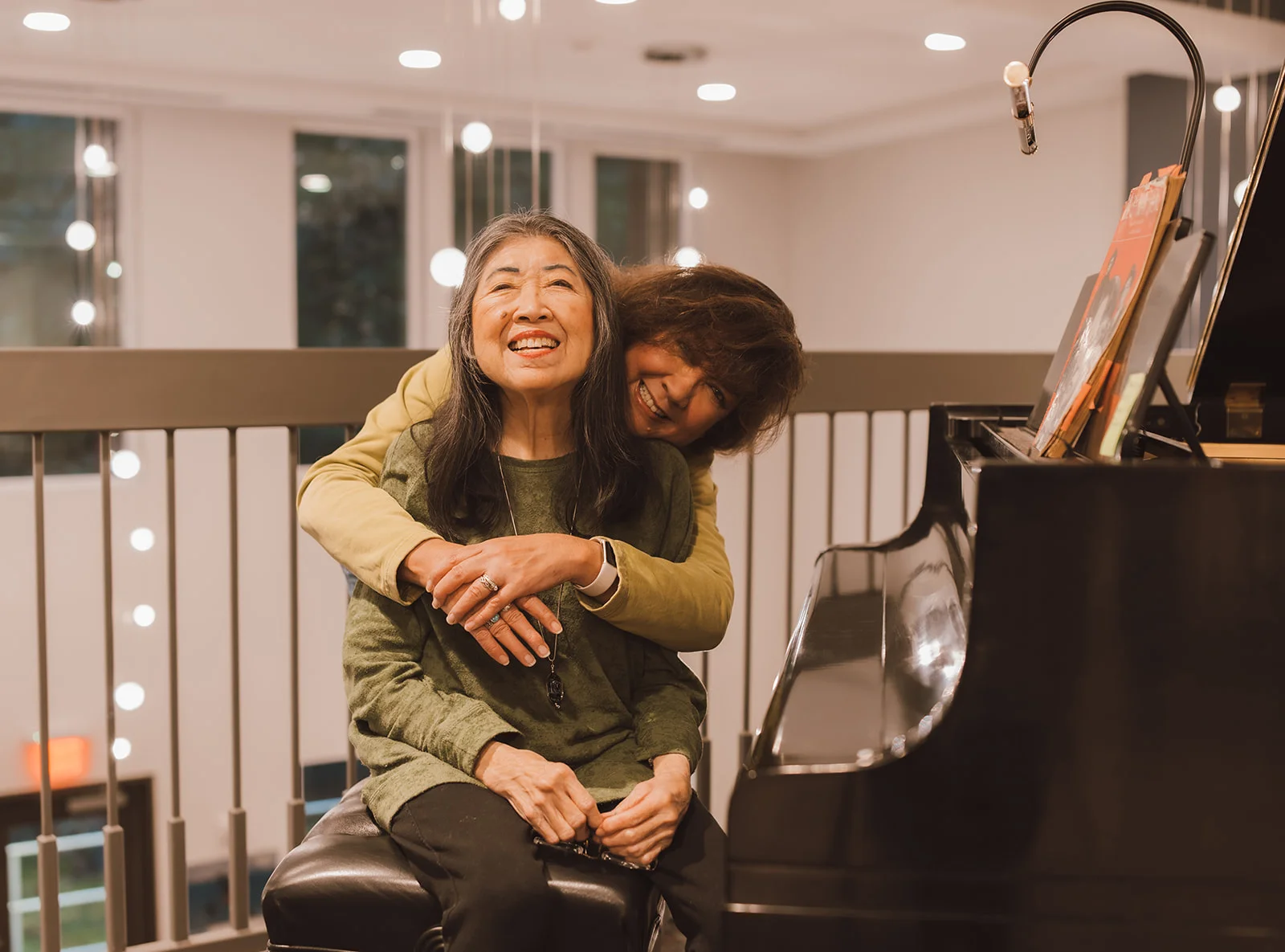 woman embracing another next to piano