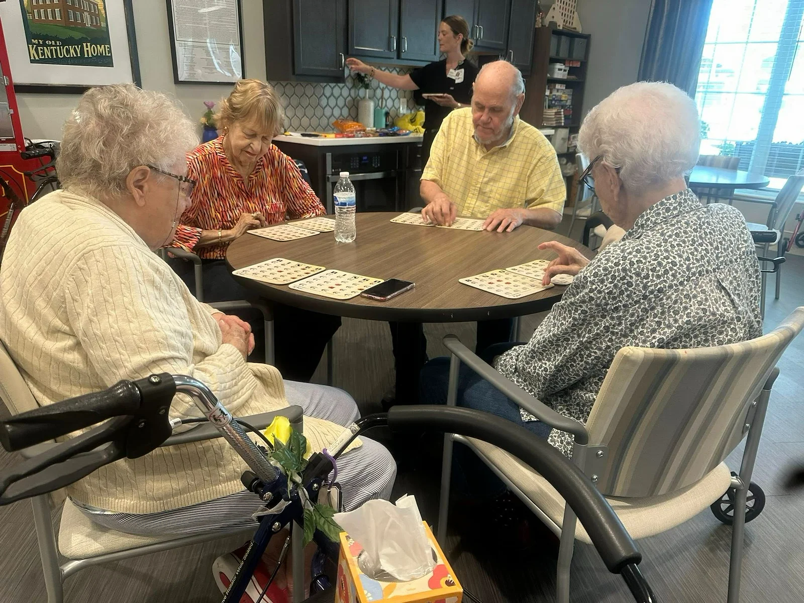 Seniors at Charter Senior Living of Hopkinsville in Hopkinsville, KY, gathered around a common table playing Bingo, fostering social connection in assisted living and memory care.