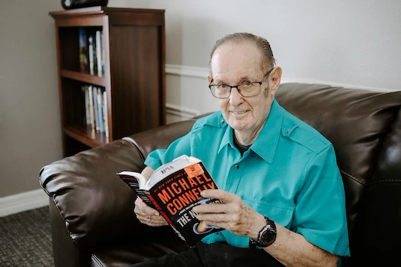 Resident reading beside bookshelf