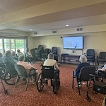 Seniors at Charter Senior Living of Hasmer Lake in Jackson, WI, enjoying a group game on a TV screen that encourages socialization and engagement.