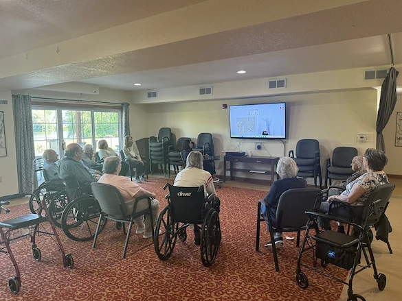 Seniors at Charter Senior Living of Hasmer Lake in Jackson, WI, enjoying a group game on a TV screen that encourages socialization and engagement.