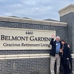 Belmont Gardens Gracious Retirement Living Hawthorn Senior Independent Living in Woodbridge, Virginia resident in front of the front entrance welcome sign