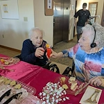 Seniors in assisted living and memory care at Charter Senior Living of Hasmer Lake in Jackson, WI, cheering with drinks and enjoying snacks together, fostering community and celebration