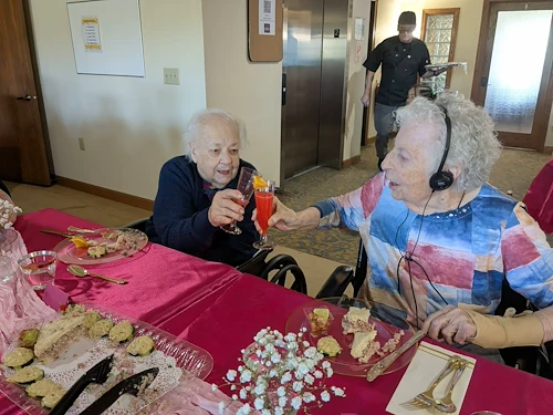 Seniors in assisted living and memory care at Charter Senior Living of Hasmer Lake in Jackson, WI, cheering with drinks and enjoying snacks together, fostering community and celebration